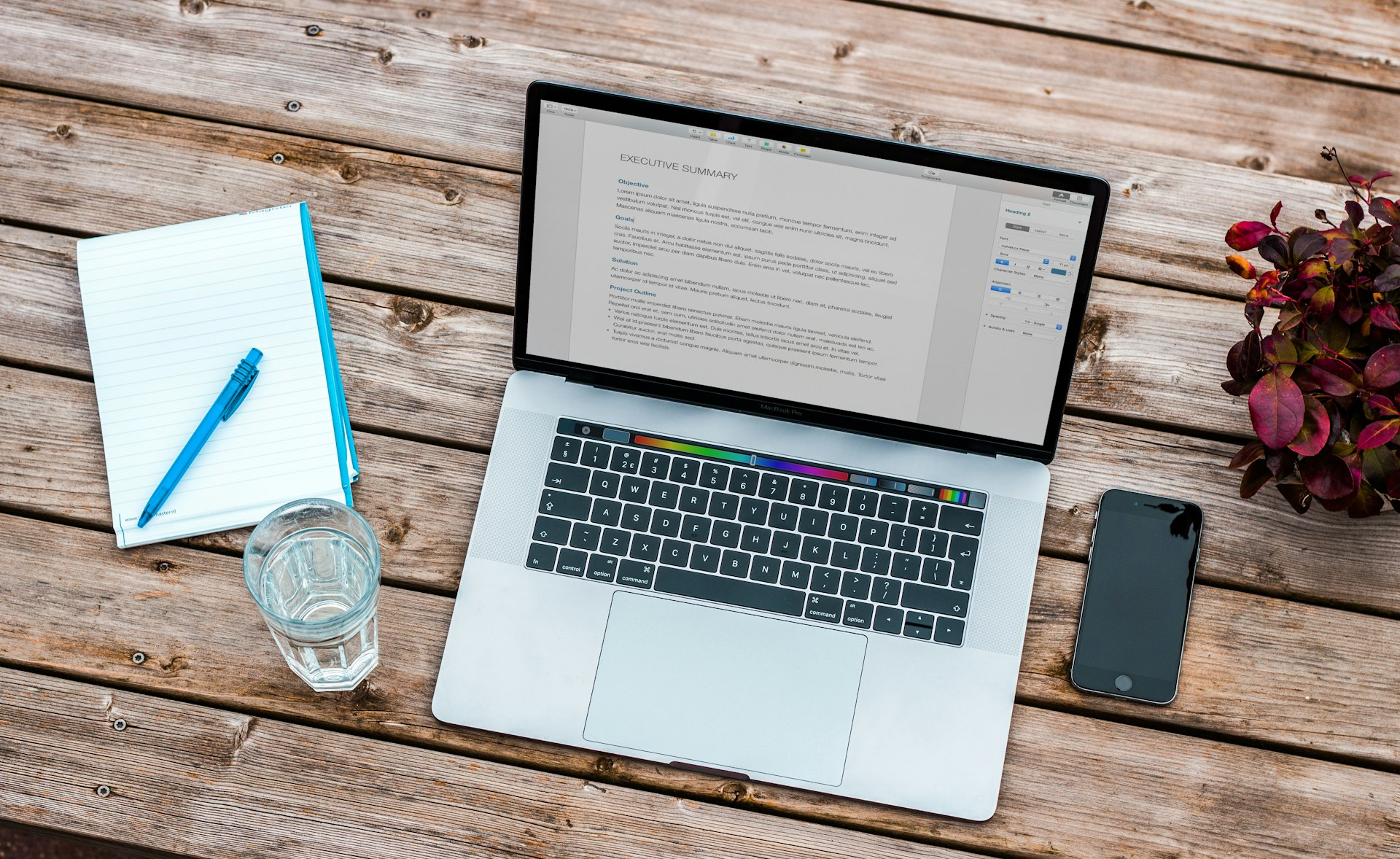 silver MacBook beside space gray iPhone 6 and clear drinking glass on brown wooden top